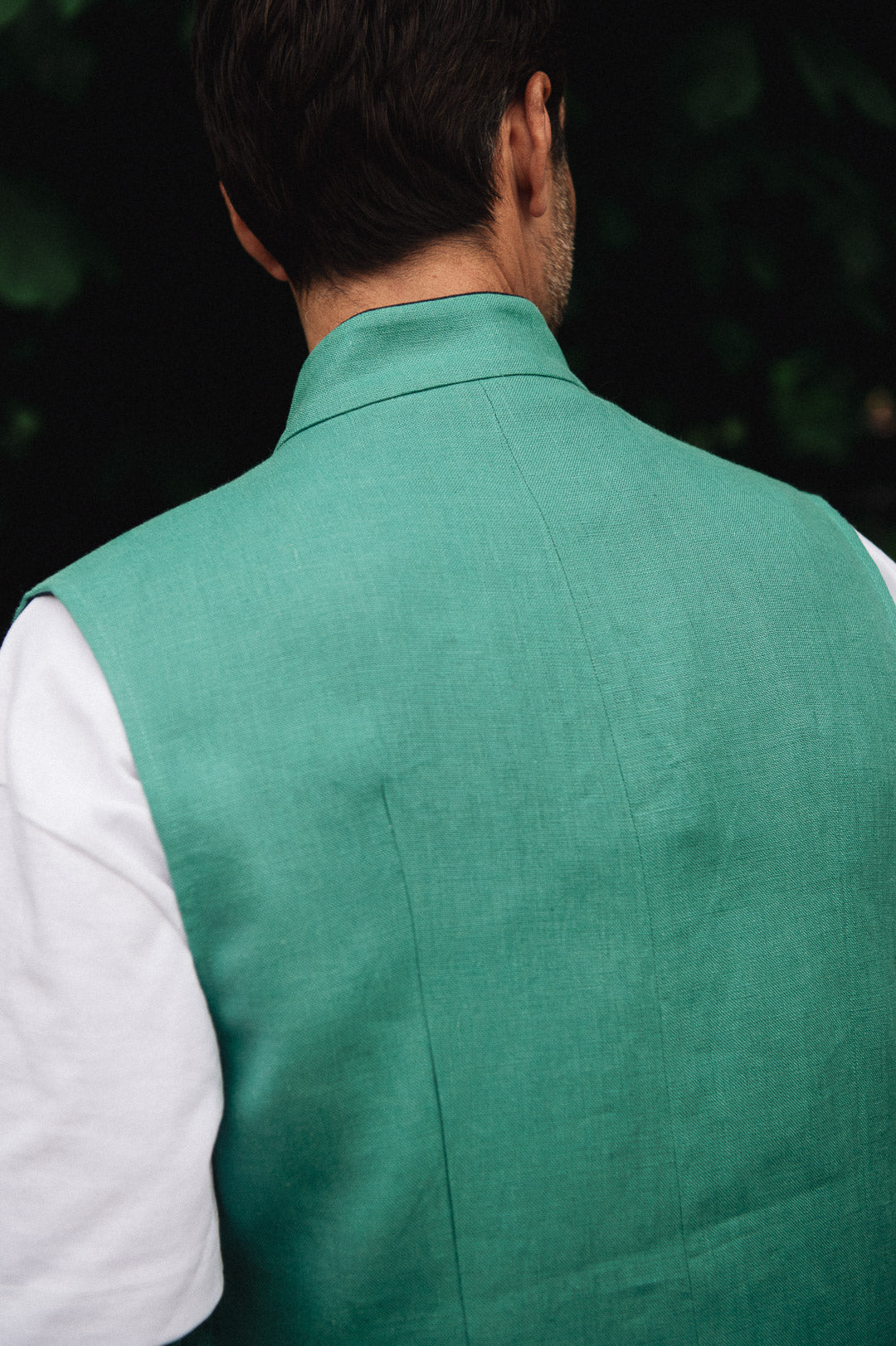 Man wearing a Darzi green vest over a white shirt - focused on back
