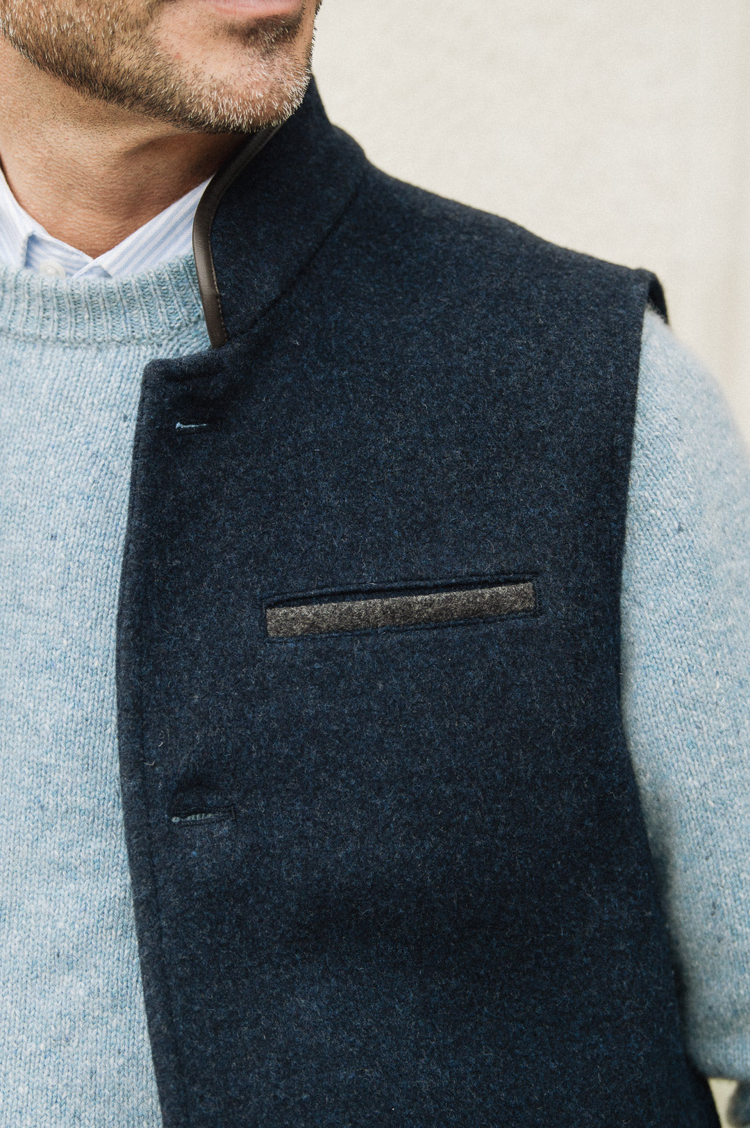 Man wearing a Darzi Midnight Blue merino wool waistcoat over light blue sweater against a neutral background