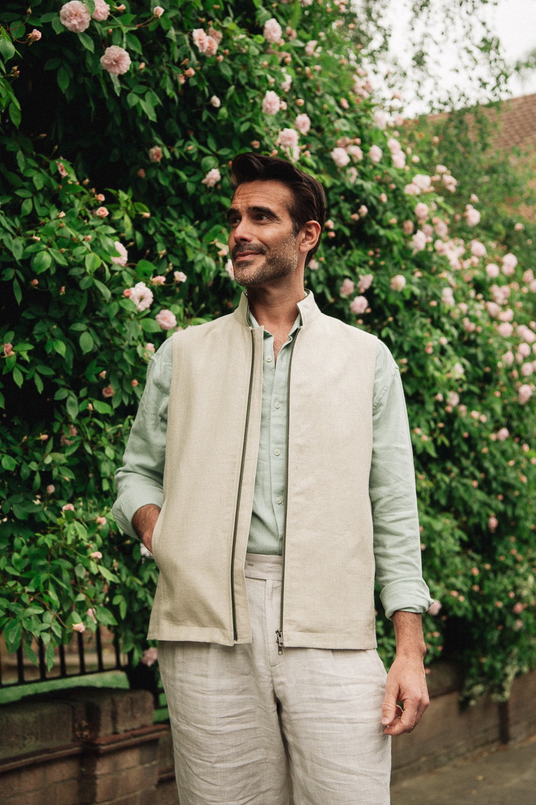 Man in Darzi limestone linen Hillgate gilet in front of a floral bush