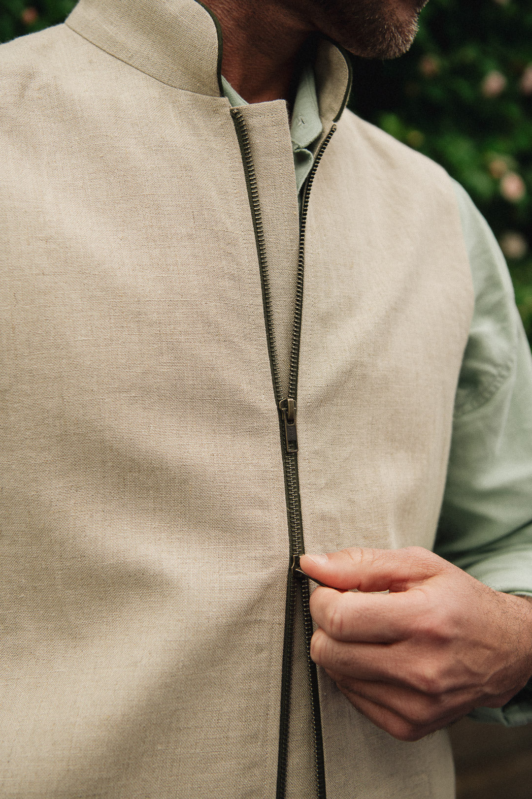 Close-up of a person wearing a Darzi limestone linen gilet with a double zip.