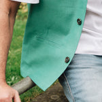 Person wearing a Darzi green linen waistcoat over a white shirt with a blurred natural background