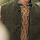 Man wearing a brown cable knit sweater under a dark green Darzi wool Helmsley waistcoat