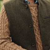 Man wearing a brown cable knit sweater under a dark green Darzi wool Helmsley waistcoat