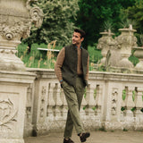 Man walking in a garden wearing a Darzi Helmsley wool waistcoat surrounded by Italianate  sculptures and greenery