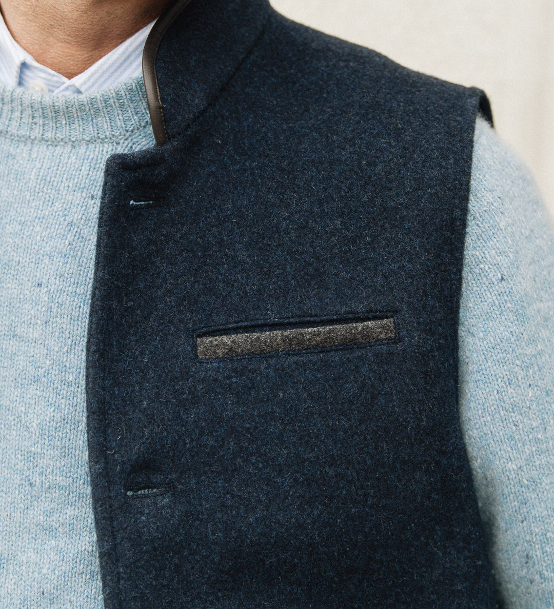 Man wearing a Darzi Midnight Blue merino wool waistcoat over light blue sweater against a neutral background