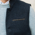 Man wearing a Darzi Midnight Blue merino wool waistcoat over light blue sweater against a neutral background
