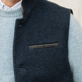 Man wearing a Darzi Midnight Blue merino wool waistcoat over light blue sweater against a neutral background