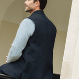 Man wearing a Darzi Midnight Blue merino wool waistcoat, sitting on a black railing - back detail