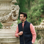 Man wearing a Darzi Hillgate heavyweight midnight blue merino wool gilet over a pink sweater