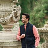 Man wearing a Darzi Hillgate heavyweight midnight blue merino wool gilet over a pink sweater