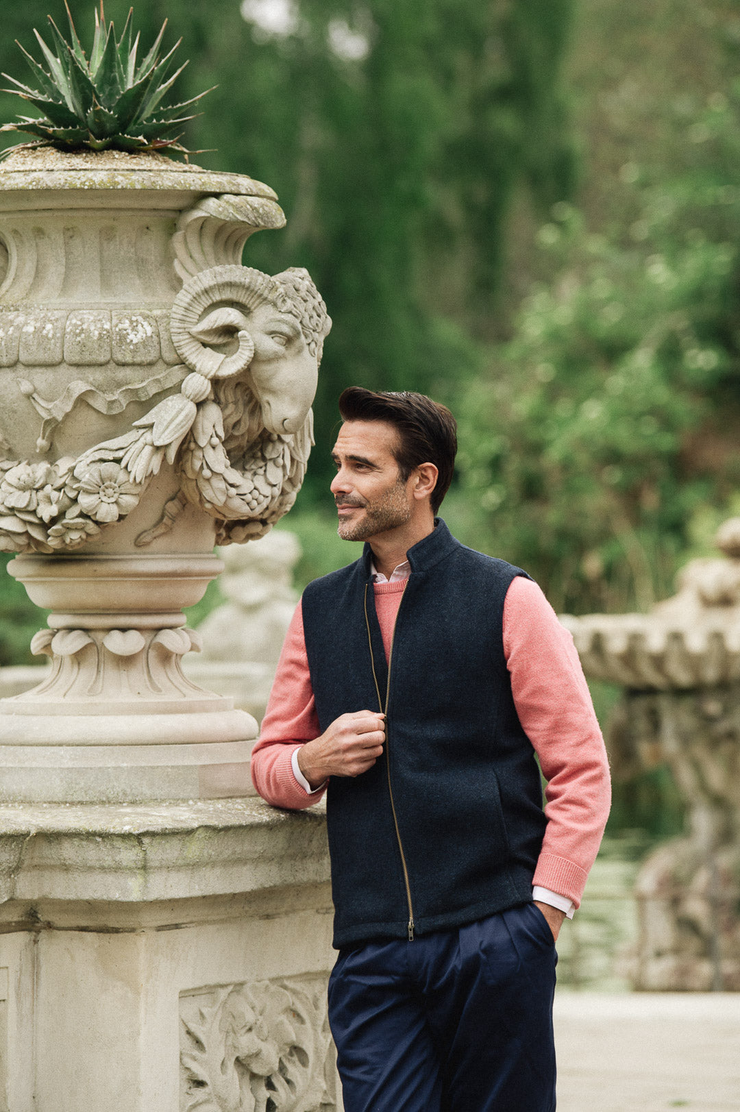 Man wearing a Darzi Hillgate heavyweight midnight blue merino wool gilet over a pink sweater