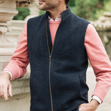 Man wearing a navy Darzi merino wool gilet over a pink sweater with a blurred natural background