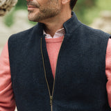 Man wearing a navy Darzi merino wool gilet over a pink sweater with a blurred natural background