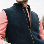 Man wearing a Darzi Hillgate heavyweight midnight blue merino wool gilet over a pink sweater