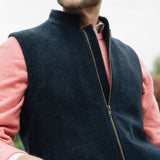 Man wearing a Darzi Hillgate heavyweight midnight blue merino wool gilet over a pink sweater
