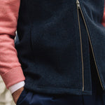 Man wearing a Darzi Hillgate heavyweight midnight blue merino wool gilet over a pink sweater - double brass zip close-up
