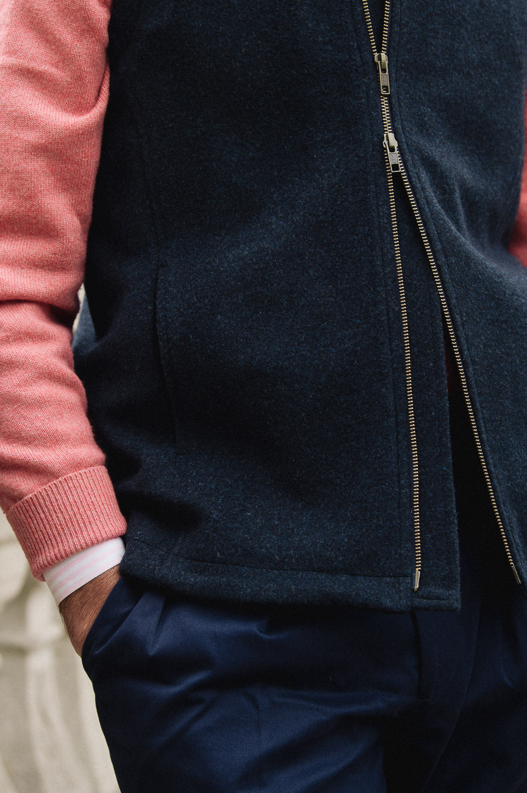 Man wearing a Darzi Hillgate heavyweight midnight blue merino wool gilet over a pink sweater - double brass zip close-up