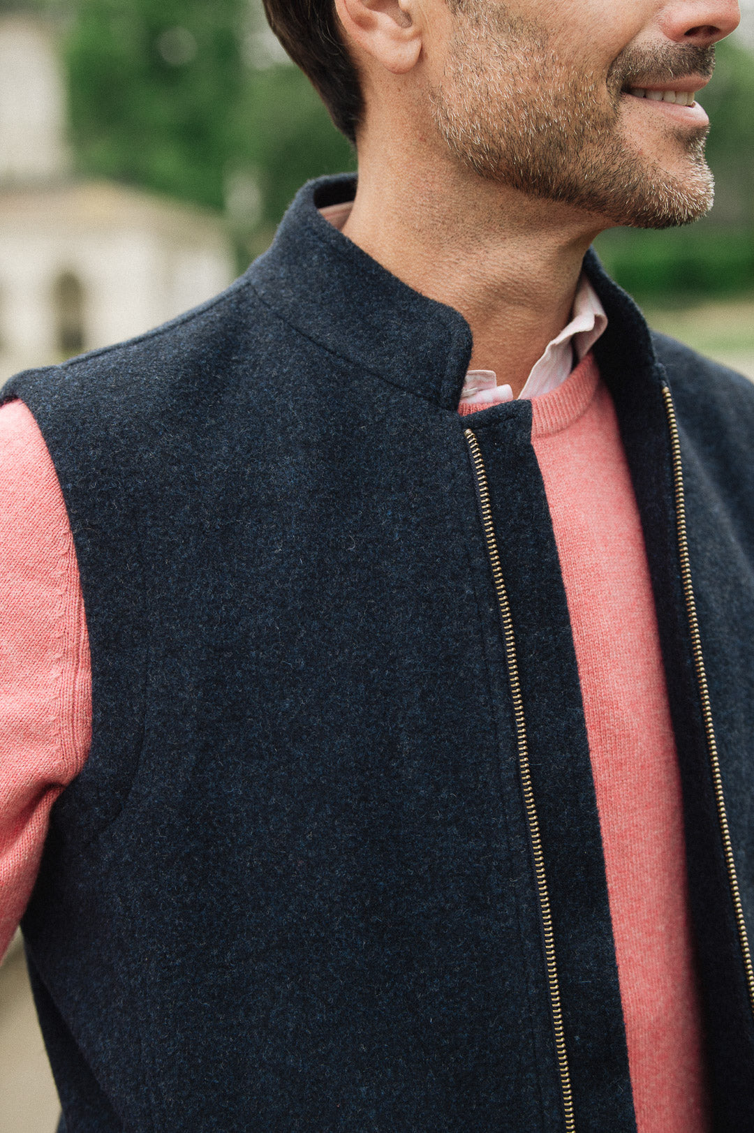 Man wearing a Darzi Hillgate heavyweight midnight blue merino wool gilet over a pink sweater