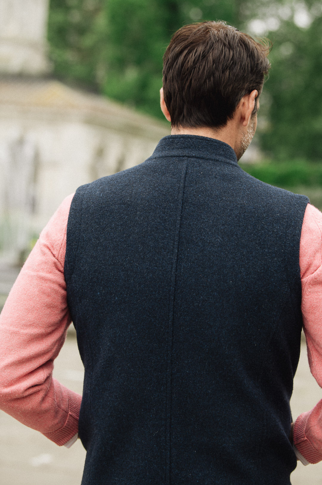 Man wearing a Darzi Hillgate heavyweight midnight blue merino wool gilet over a pink sweater - shown from behind