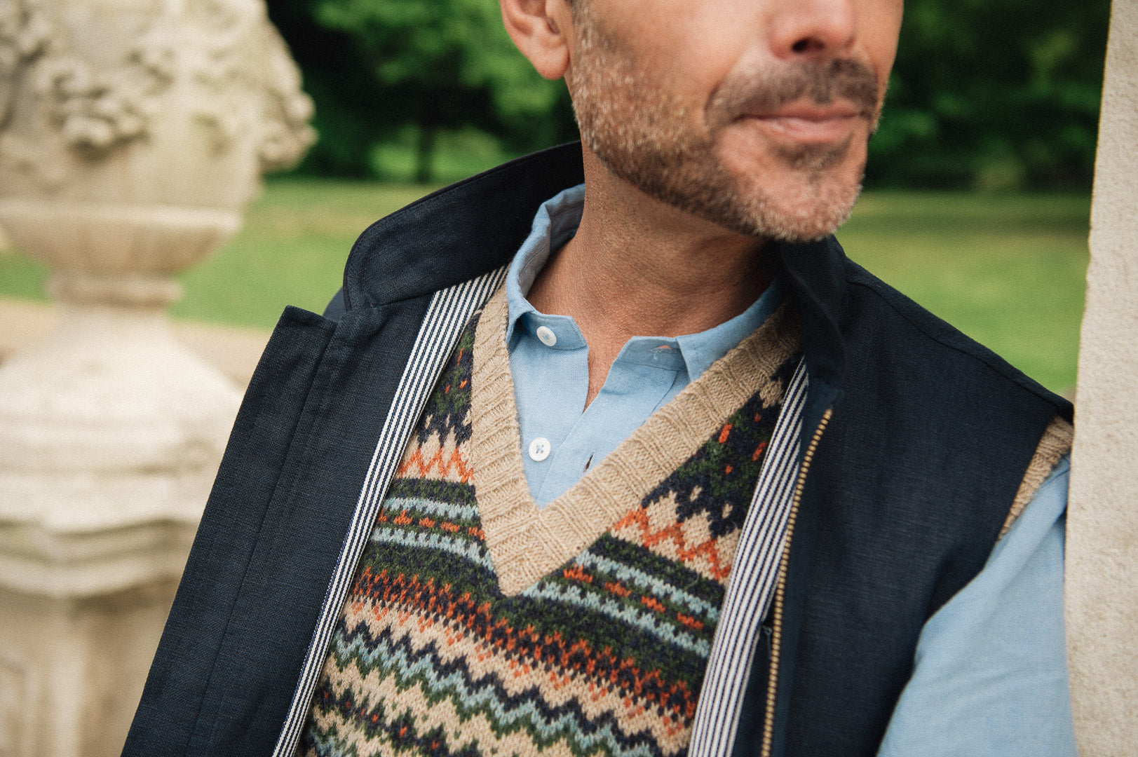 Man wearing a wearing a British made Darzi navy linen Hillgate gilet over a blue shirt in an outdoor setting