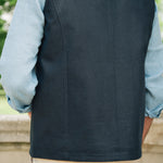 Person wearing a Darzi navy linen Hillgate gilet over a light blue shirt with beige pants, standing outdoors.
