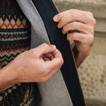Person wearing a patterned sweater and Darzi navy linen Hillgate vest, showing concealed inside breast pocket opening