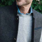 Man standing outdoors wearing a Darzi Helmsley wool waistcoat in Blue Brown Twill over a grey sweater