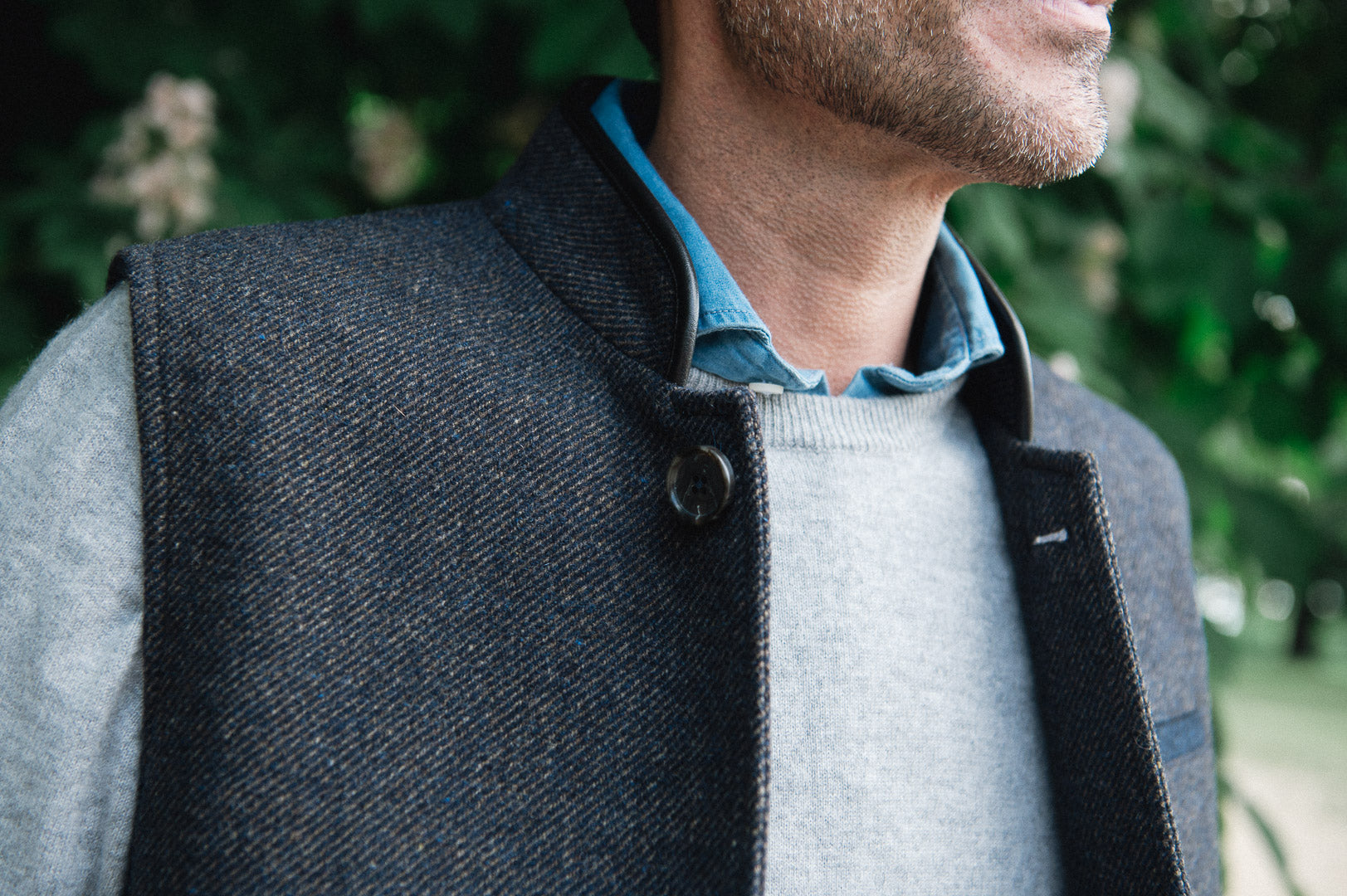 Man wearing a Darzi Helmsley wool waistcoat in Blue Brown Twill over a grey sweater and blue collared shirt - close-up image