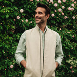 Man wearing a Darzi limestone linen Hillgate gilet standing in front of a rose bush