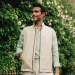 Man in Darzi limestone linen Hillgate gilet in front of a floral bush