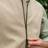 Close-up of a person wearing a Darzi limestone linen gilet with a double zip.