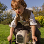 Little boy sitting on toy car wearing a Little Darzi Camel Brown wool waistcoat