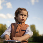 Boy wearing Little Darzi in Coral Red sitting on toy car