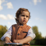 Boy wearing Little Darzi in Coral Red sitting on toy car